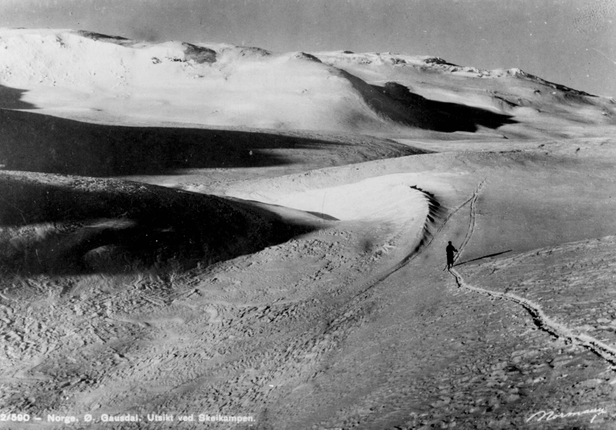 Avfotografert postkort. Utsikt over Skeikampen med en enslig skiløper på vei over fjellviddene.