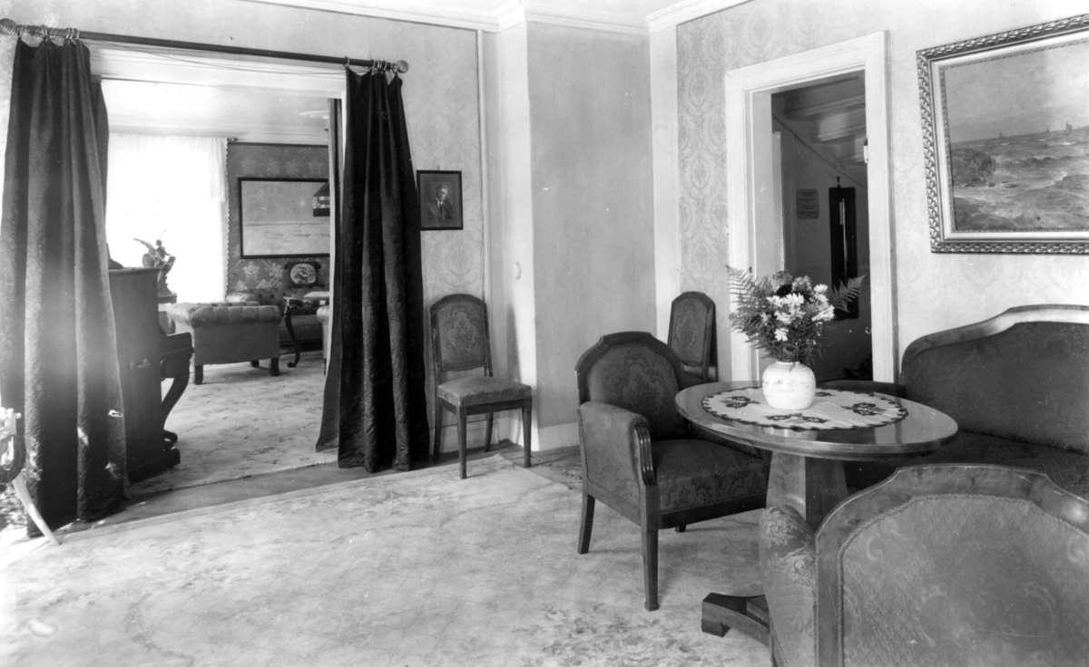 Roald Amundsens hjem, Svartskog. 1935.
Interiør. Stue. Møbler til høyre. Gjennom dør med portierer utsikt til stue. Blomster.