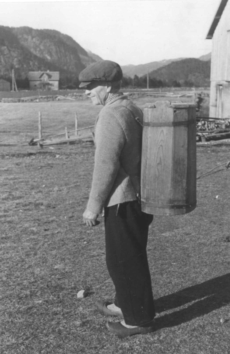 Ola Endreson bærer "mjølstrykkje", melbeholder av tre til ha på ryggen. Åseral, 1943.
