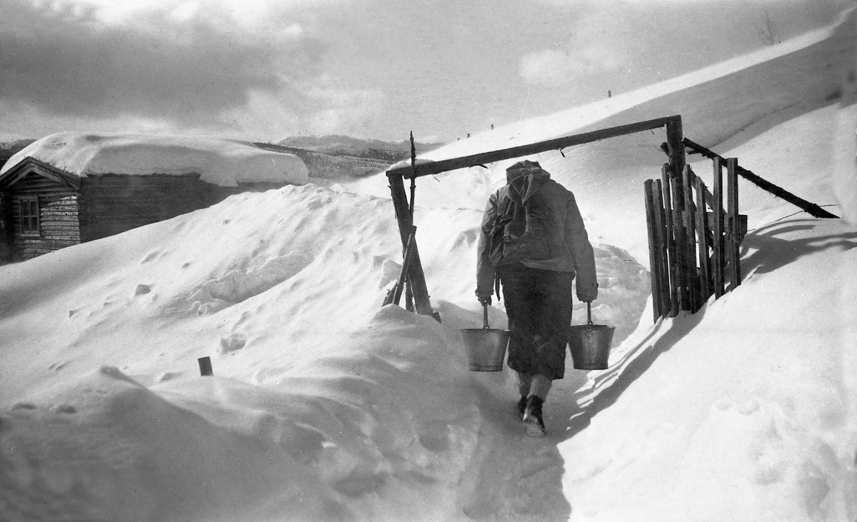 En mann bærer vann og ryggsekk opp til hytta Ligardshaugen, Eggedal. Fotografert 1947.