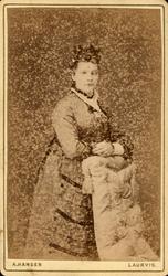 Visittkort. Portrett av kvinne stående bak en stol.