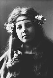 Studioportrett av kvinne i kostyme med mørk overdel og bloms