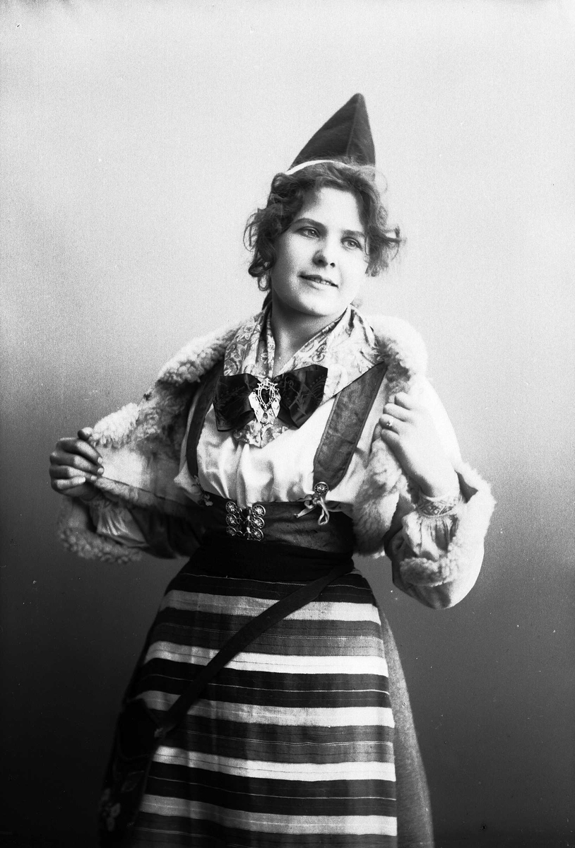 Kvinne i drakt - kort skinnjakke med pelskanter og lue.