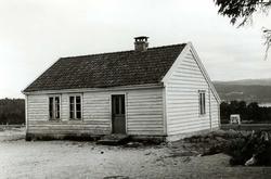 Natås, Lindås, Hordaland. Lite hvitt skolehus, sett fra gård