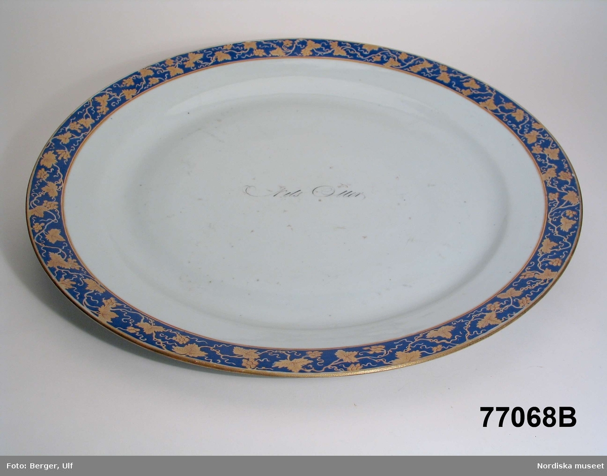 Montertext i Dukade bord: Punschbål med fat av kinesiskt porslin med dekor i blått och guld samt text "Nils Oller", ca 1800. 