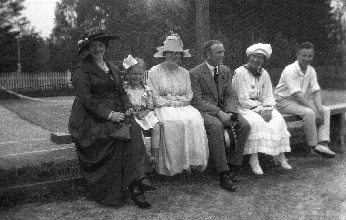 Tre kvinner, to menn og en liten jente på tilskuerbenken til tennisbane i Trondheim. I denne gruppen er bl.a. fru Grüner og Andreas Bugge.