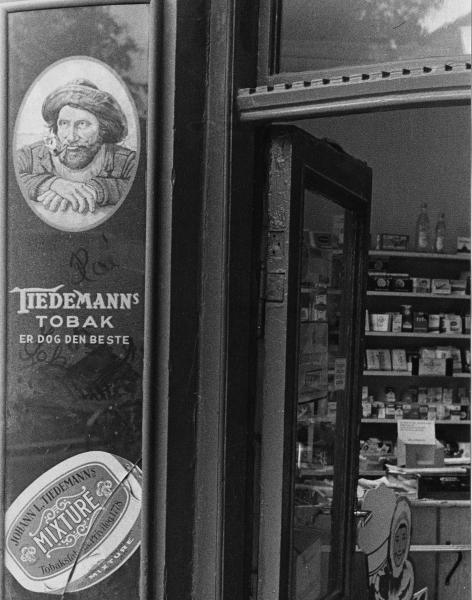 Gatebilde. Kiosk med reklame for tobakk ved inngangen.