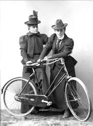 Gruppeportrett, to unge kvinner med damesykkel.