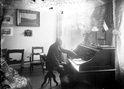 Portrett, mann ved skrivebord i stueinteriør, ukjent sted.