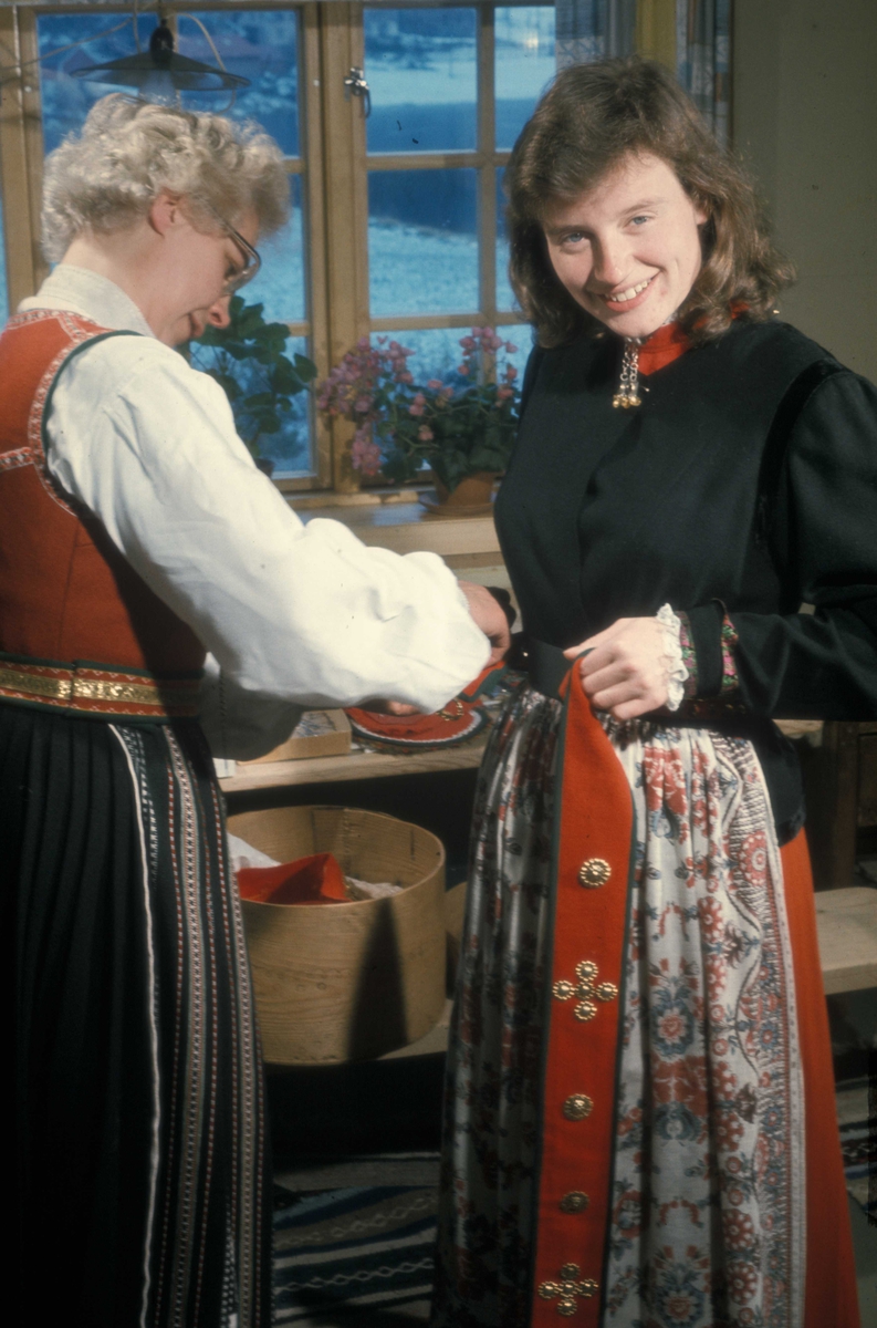 Brudepynting, Jølster 1967. Bruden, Eva Eide, får hjelp av Maria Gjesdal med påkledningen. Her festes sølvbeltet.