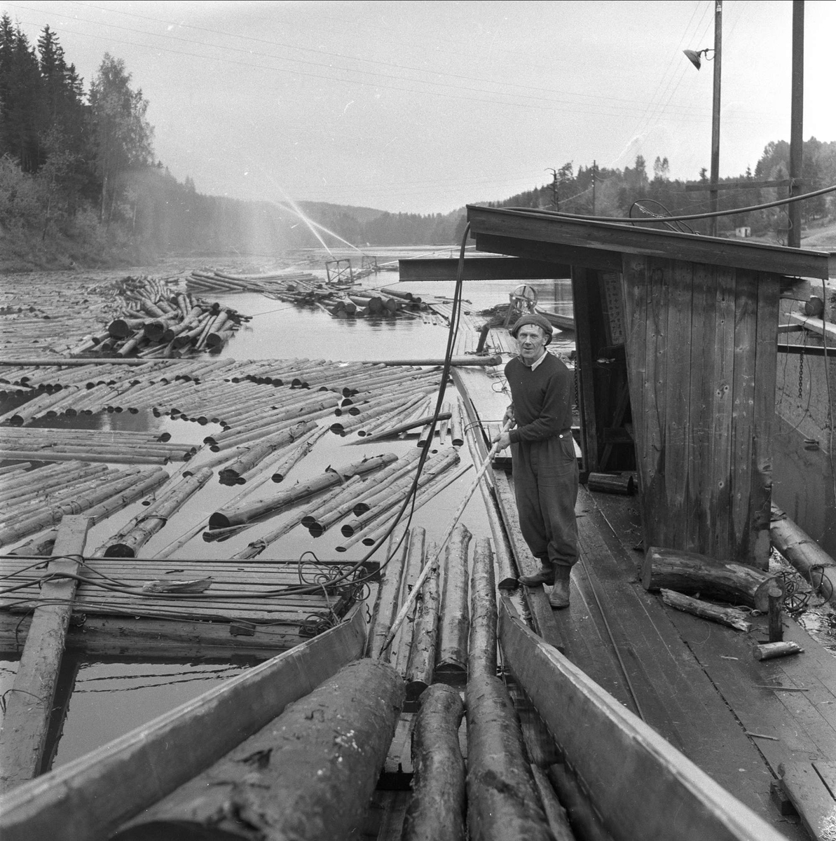 Holmen Brug i Hokksund, Øvre Eiker, Buskerud, 02.10.1958. Mann jobber med tømmer på elv.