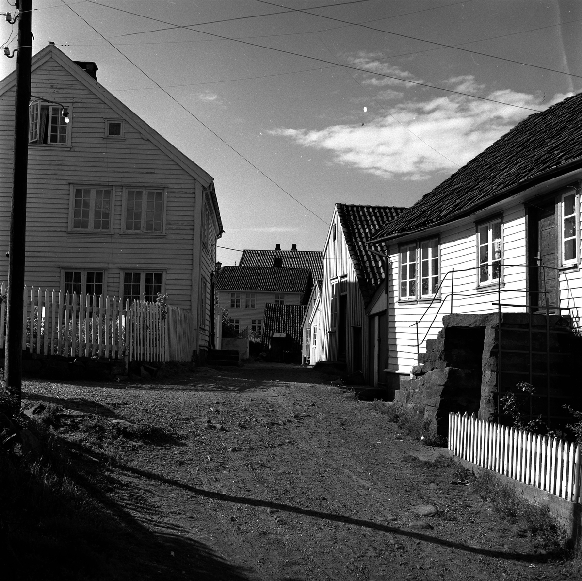 Sogndalsstranda, Sokndal, Rogaland, juli 1956. Gatebilde med trehus, boliger og uthus.