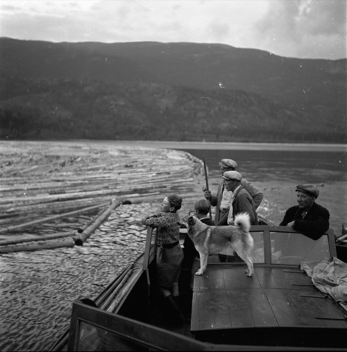 Tømmerfløtere i Sperillen, Ringerike, Buskerud, ant. 1950-tallet. Gruppe i båt utenfor lensene.