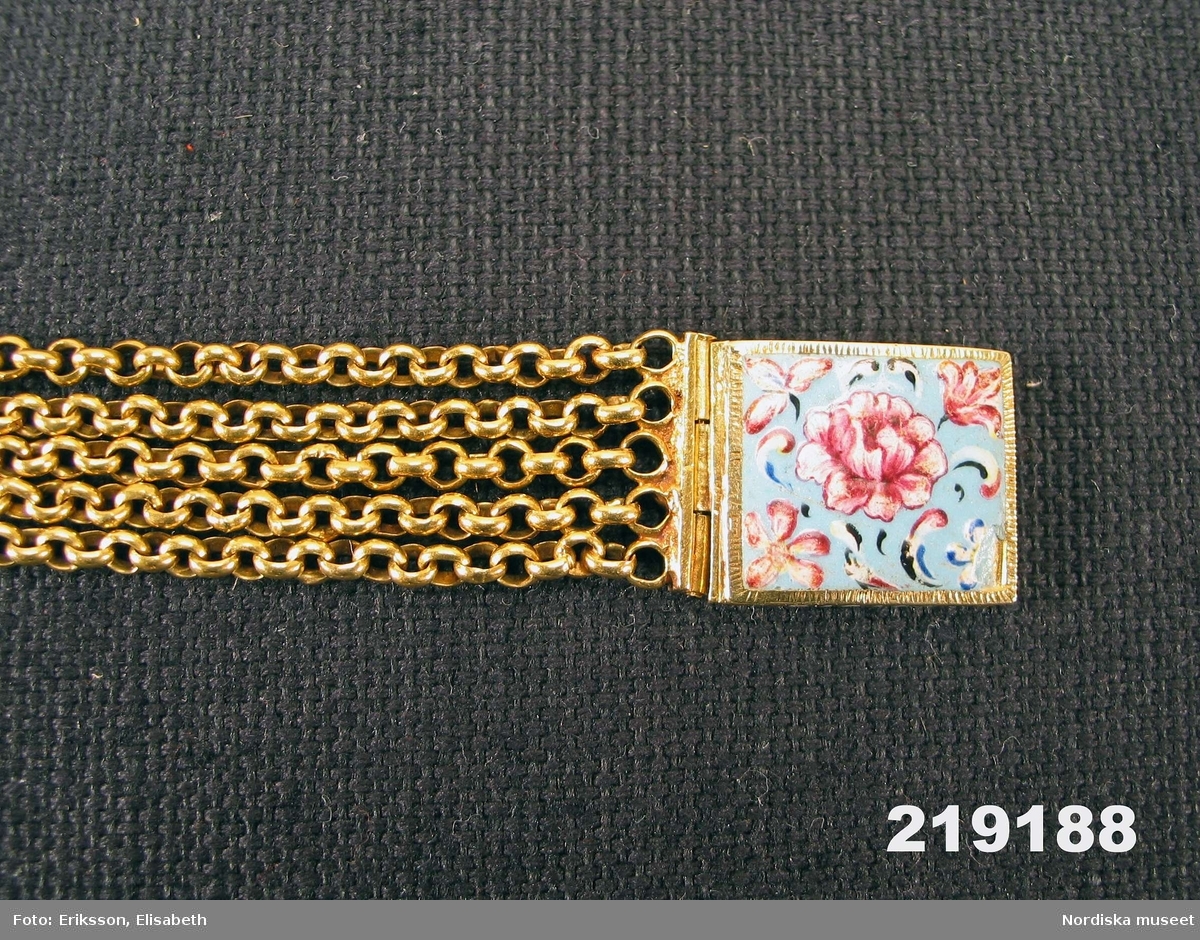 Halskedja av guld bestående av sex stycken kedjelänkar av ankartyp med cirkelrunda länkar. Rektangulärt lås av instickstyp med emaljmålning föreställande blomstermotiv i färgerna rött, vitt och svart mot blå botten. Vid låsets vardera sidor fem fasta öglor för kedjornas fäste.
Låsets baksida försett med Kung Karl XI:ss namnschiffer.
Enligt traditionen är smycket gåva av Karl XI till kyrkoherden Karsten Rönnow i Åhus, Skåne för att han vid ett tillfälle under det svensk-danska kriget 1676 - 1679 frälste konungens liv genom att gömma honom i en skorsten.
/2008-01-16 Ingrid Roos
Utdrag ur Kongl. Antiqvitets Archivets Inventarium år 1855: Inv.nr 21116.---Denna kedja--hade blifvit såld av någon Presten Rönnows ättling till en antiqvitetssamlare, Kopparslagaren Lang i Malmö, från hvilken den gått i arf till Kapten vid Kongl.Ingeniör Corpsen A.Wiggman, som sålde den till Museum för 167 Rd. 8 sk. B:co. Den betaltes efter 5 Rd. 32 sk. B:co lodet.
