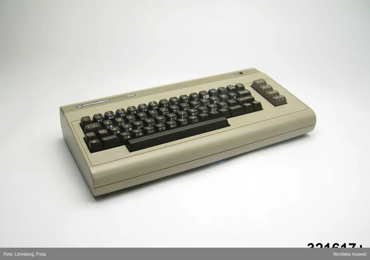 Inventering Sesam 1996-1999:
L 42 cm
B 19 cm
Tangentbord i ljusgrå plast med bruna tangenter för bokstäver, siffror, shift, return mm. Längs överkanten sex präglade linjer med t v C Commodore 64 med silvriga bokstäver mot mörkgrö bakgrund samt emellan Commodore och 64 fem linjer i spektrumfärger I hö överkanten texten "Power" samt röd lampa. På baksidan olika uttag för "Memory expansion / H-L / video, serial.cassette / User Port". På undersidan tre etiketter. Mittetiketten har svart text mot silverfärgad bakgrund "C Commodere, C 64, Allg.Gen.n.DBP-Vfg. 529/70, 5 V =; 9 V  15 W, Ser NO U.K. B1602602, Made in England". Vid sidan om röd pappersetikett "TRICOM DATA SERVICE, Birkagatan 17, 11336 Stockholm, Tel. 087736 02 91.
En svart sladd är kopplad till uttaget RF.
Vid spel kopplades tangentbordet till en vanlig TV, en vanlig bandspelare och en transformator.
Dataspel och tillhörande föremål; Tangentbord ivn.nr 321.617 kasettbandspelare inv.nr 321.618, transformator inv.nr 321.619, Kasettväska med kasettband med olika dataspel inv.nr 321.620:1-24, tre joy sticks inv.nr 321.621 och 321.622, skokartong inv.nr 321.623 (i vilka kasettband förvarades)  och Kasettband med spel 321.624-321.639
Instruktionsböcker, band- och kundförteckning finns på arkivet.
Axel Brundin (född 1977) fick datorn i julklapp. Den var köpt från pojkarna Norman (födda 1971) som tidigare använt den.
Bilaga, Se även Nordiska museets årsbok Fataburen 1998 "Känn dig själv" sid 232ff.
EB 1995 [=Elisabet Brundin]