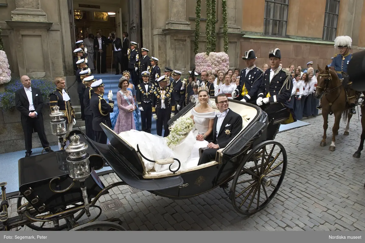 Kronprinsessbröllopet den 19 juni 2010. Kronprinsessan Victoria och prins Daniel i vagn utanför Storkyrkan i Stockholm. I bakgrunden H.M. kung Carl XVI Gustaf, drottning Silvia, prins Carl Philip och prinsessan Madeleine.