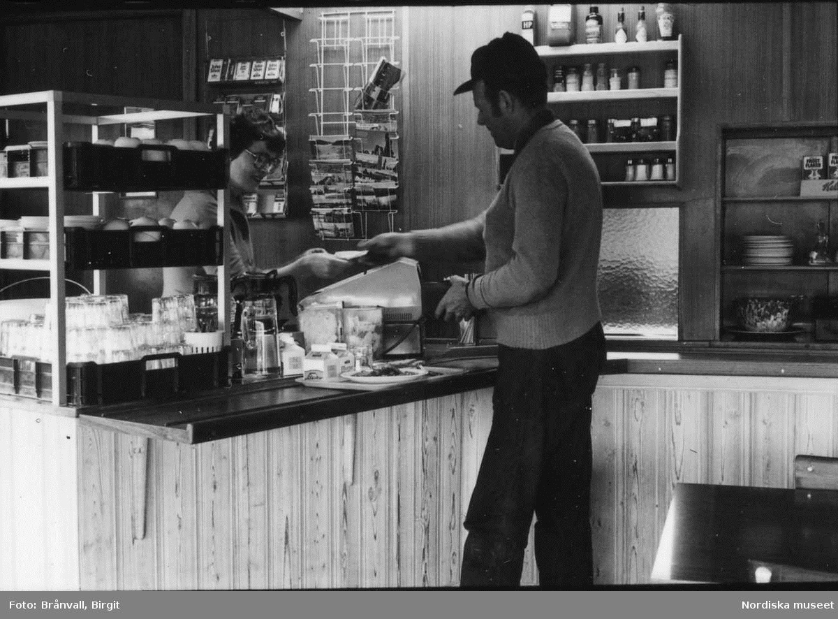 Storuman 1982. Bar i centrum. Interiör från matservering, köksperonal, matgäster, beställningsdisk, barnfamilj.