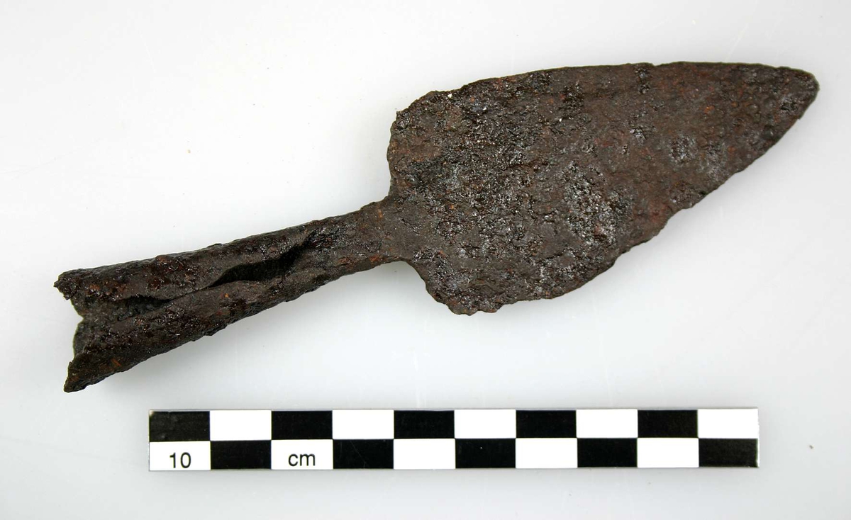 Spjutspets med holk, av järn. Holken är klen, lite "fult" gjord, inte helt sluten. Spetsen kommer sannolikt från ett jaktspjut (kastspjut), troligen för säl. Möjlig datering folkvandringstid (400-600 e.Kr.).