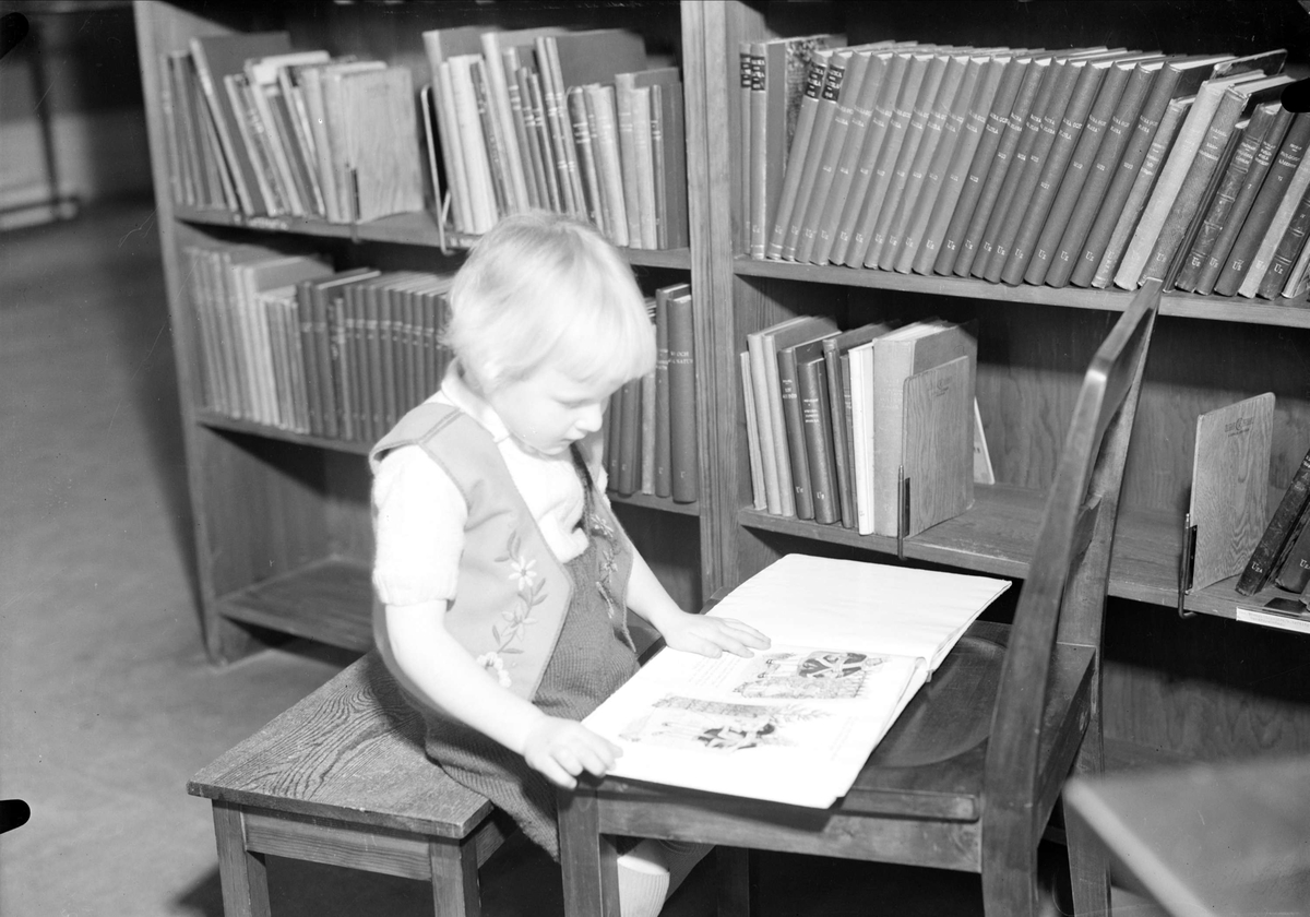 Barn läser bok, sannolikt på Uppsala stadsbibliotek, Uppsala