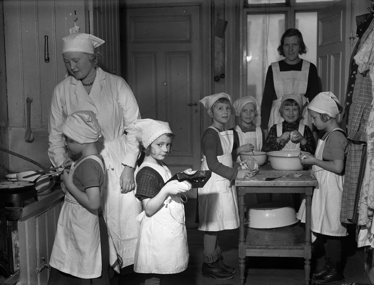 "Småflickor under sakkunnig ledning pröva sin färdighet i matlagning i barnträdgårdens kök" - Etisk-Pedagogiska Institutet, Trädgårdsgatan 12