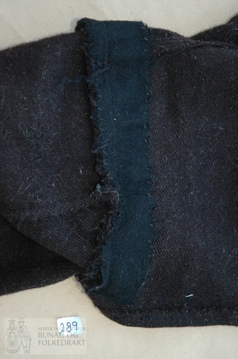 Gråkupte i kypertvevet brun vadmel, ufôret. Svart klede / ullflanell til kanting på krage, framsykker (frambloke) og nederkant ermer. Broderi (løyesaum) på krage, framkant og nederkant erme. Sømmonnet i sammensyingssømmene et lagt til hver side og stukket ned på maskin. På vrangen på forstykkene er det sydd på et brunt ullstoff, over skulderen og nedover ryggen er det sydd på svart kypertvevet ullstoff. Dette stykket er sydd fast sammen med ermesyingssømmen, alt sømmonnet er kastet sammen for hånd med svart ullgarn. Trøya har ikke sidesømmer, kun ryggsøm. Opplegget nede med lange forsting og kastet fast til bolen med kastesting for hånd og ullgarn.

Tosømserme i fasong, glatt isydd. 4 filegransknapper i sølv på hvert erme, ved ermesplitten. Disse er festet med skinnsnor på vrangen. Ermesplitten er fastsydd.
Kragen er sydd til bolen med maskin. Sømmonnet er brettet mot bolen og kastet fast for hånd med svart ullgarn.