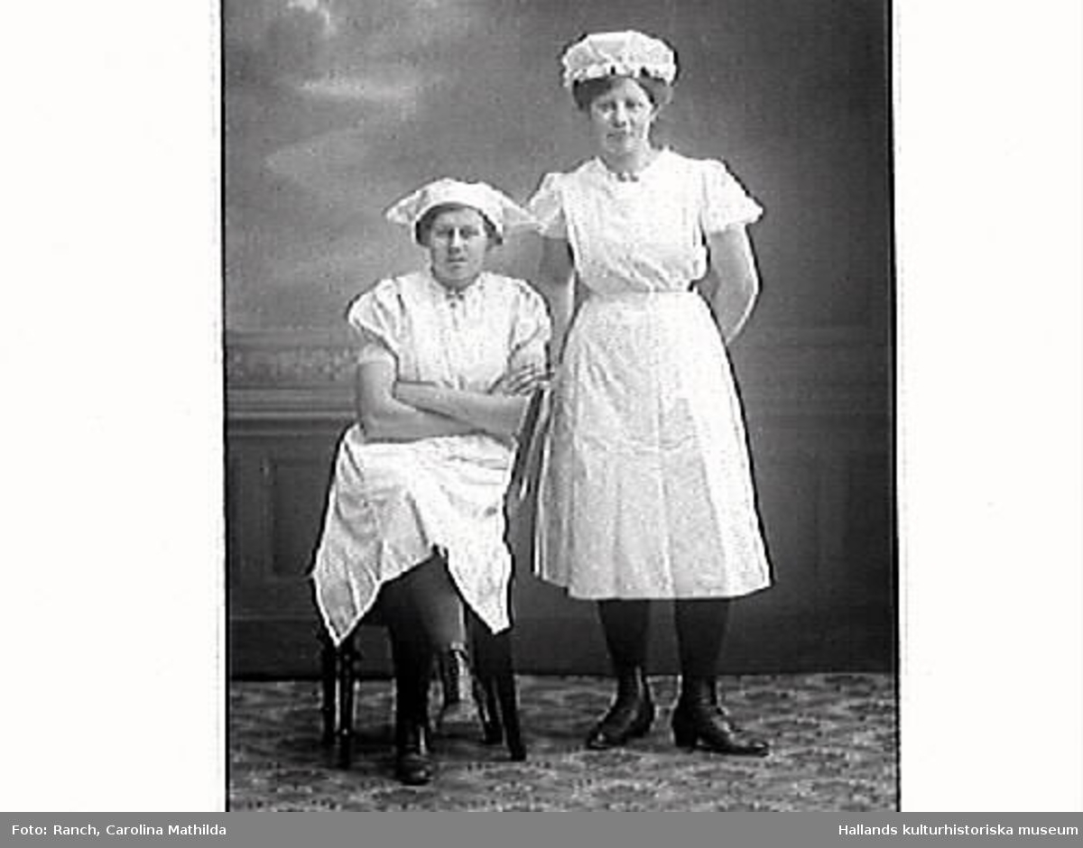 Två kvinnor, Ruth Adolfsson (stående) och en arbetskamrat. De arbetade mejeriarbeterskor på Istorps Mejeri. Porträtt i helfigur och halvfigur (2 bilder).