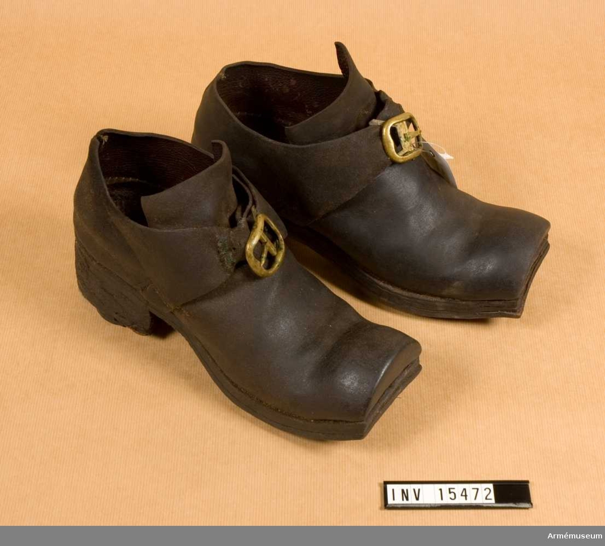 Grupp C I.
Ett par skor av brunt läder med mässingsspännen.