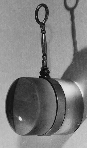 Förstoringsglas, cylinderformat med en plan och en kupad bottenyta, infattad i en ring och skaft av silver.
