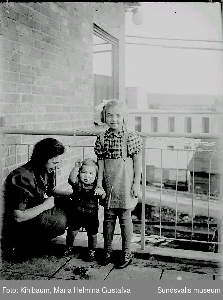 Kvinna med två barn på en balkong.