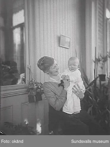 Förmodligen Pussi (Dora Louise) Norström med ett av sina barn.
Pussi var gift med direktören vid Skönvik, Ingenjören Karl Fredrik Lennart Nordström och hans mor Alma Cecilia Norström f Bünsow var gift med civilingenjör  Claes Gustav Norström.