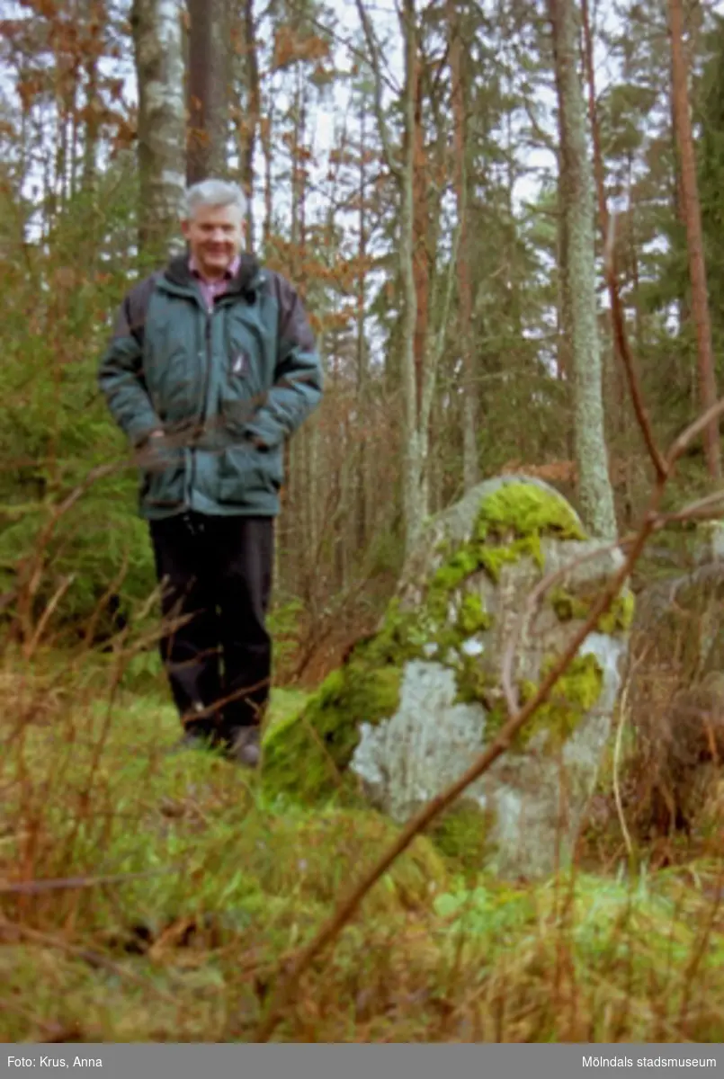 Sven-Åke Svensson står bredvid en gränssten i Tuleboskogen.