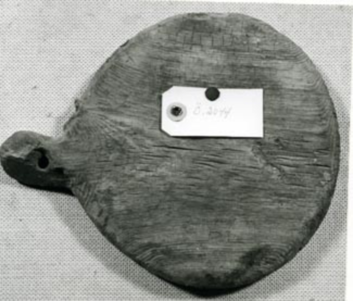 Cirkelrund med hängtapp och kvarsittande järnbult. Hål för låspinne.Sjöfynd från RIKSÄPPLET.Föremålets form: Cirkelrund