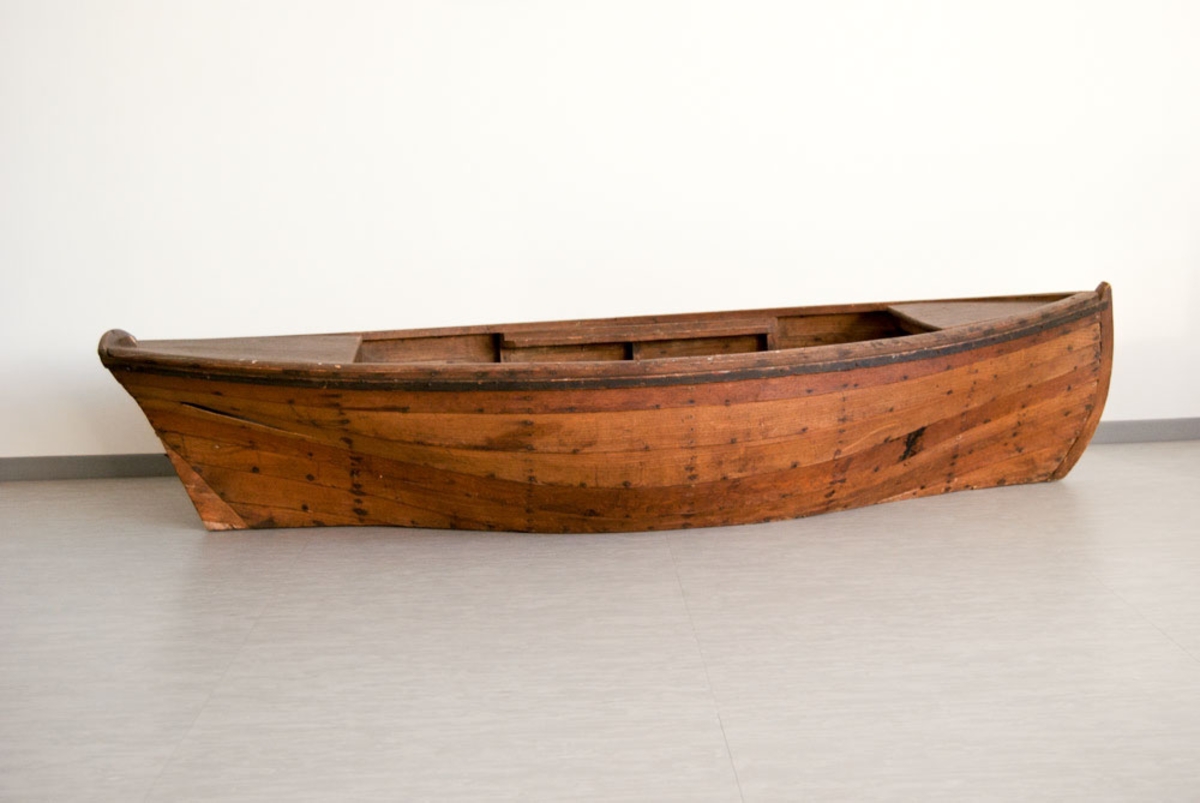 Liten båt brukt i scenografi ved E. H. Torjusens atelier.
Båten er i tre, gliper mellom bordene. Spikre slått gjennom bunnen.