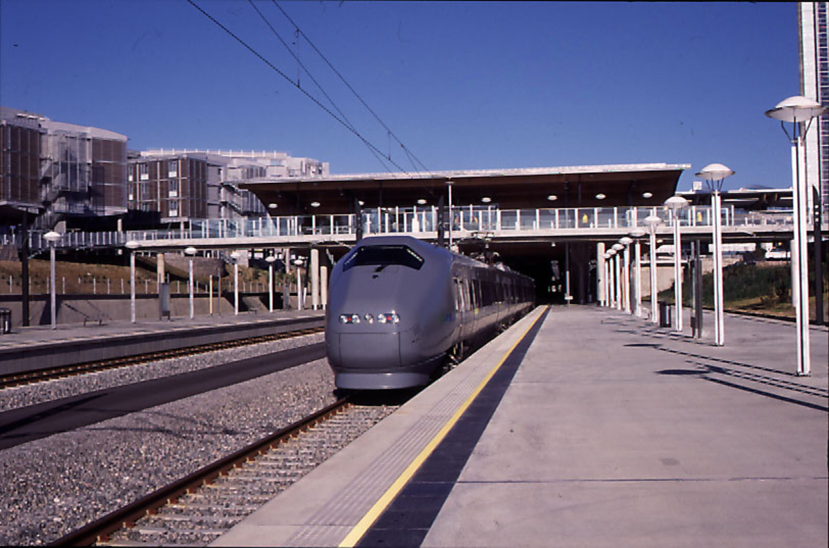 Lufthavn, 1 flytog på vei inn på togstasjonen. Terminalbygningen i ...