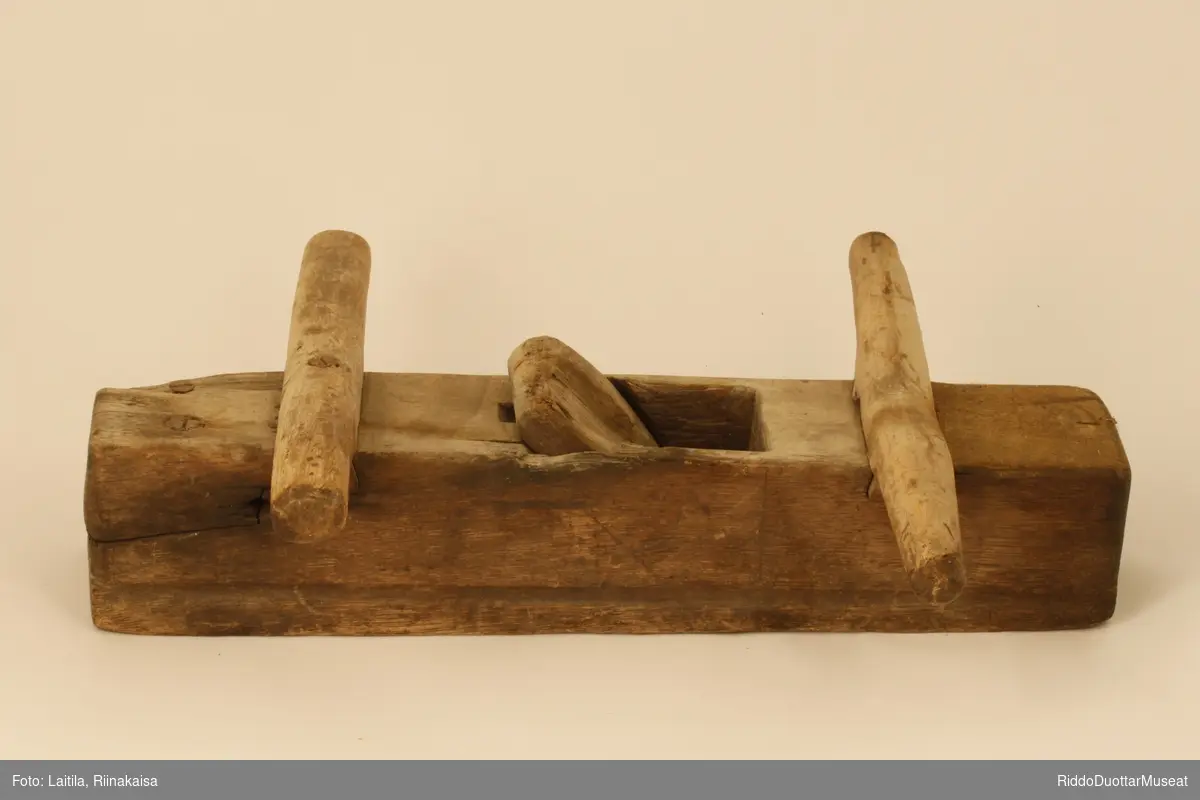 Avlang høvel laget av ett trestykke, med to pinner på tvers.