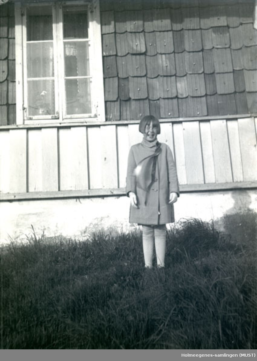 En pike med lang 17.maisløyfe foran huset på Holmeegenes i Stavanger.