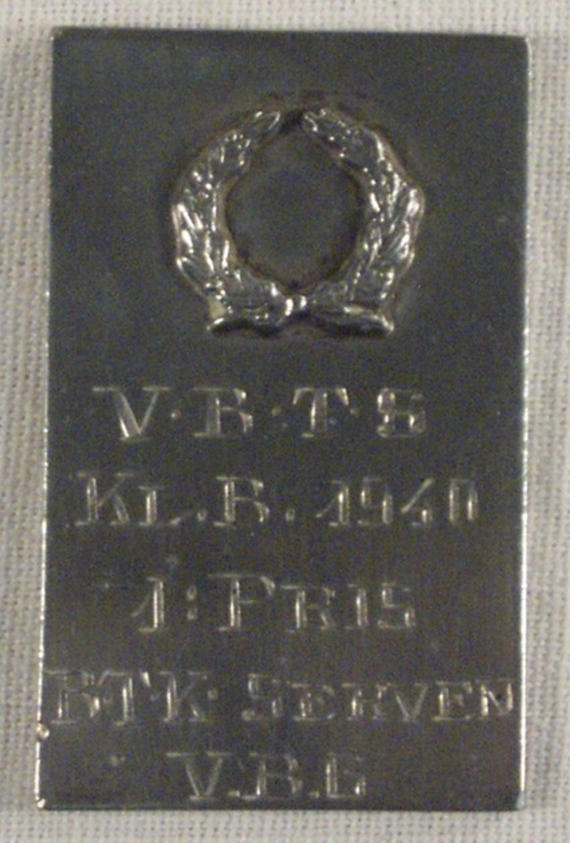 Plakett graverad med V.B.T.S, KL. B. 1940, 1: PRIS, B.T.K SERVEN. V.B.G.

Har tillhört givarens farbror Gösta Granath (1917-1981). Gösta arbetade på SAAB i Trollhättan och i Göteborg från 1956.
