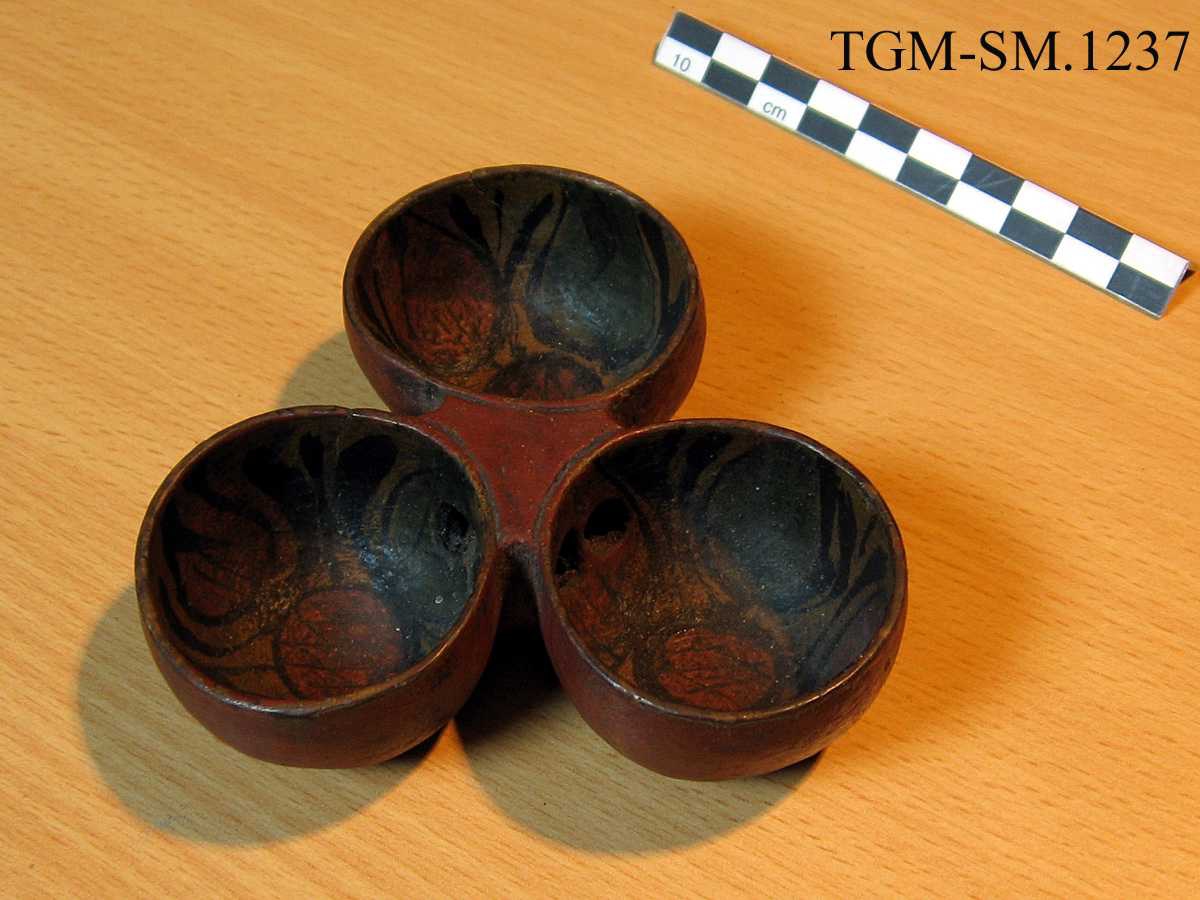 Tre mindre beger - laget av ett trestykke. Munkepanneform. Hull mellom begrene. Rødbrun maling på utsiden, rosemaling oppi begrene.