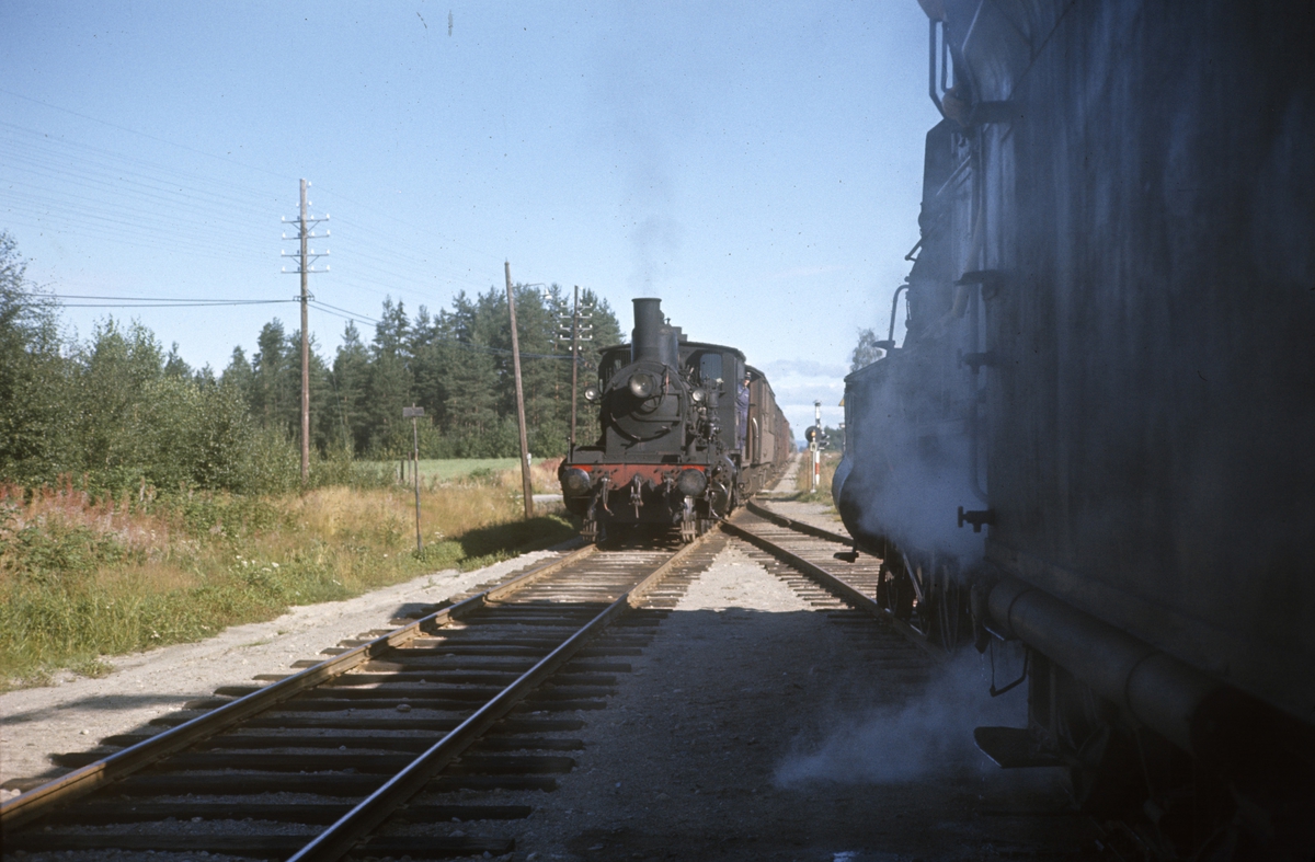Kryssing mellom to godstog på Arneberg stasjon på Solørbanen. Damplokomotiv type 27a til venstre, type 26c nr. 433 til høyre