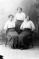 Studioportrett i helfigur av tre kvinner.