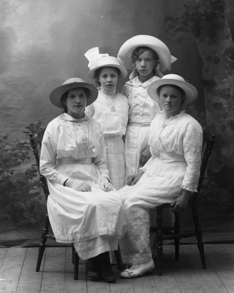 Studioportrett av fire unge kvinner i helfigur.