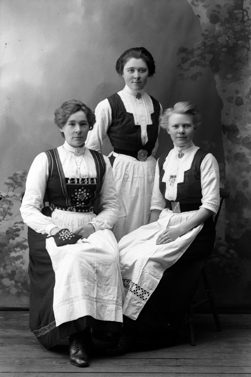 Studioportrett av tre kvinner i bunader.