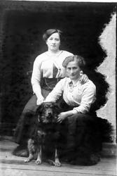 Studioportrett av to kvinner med en hund.