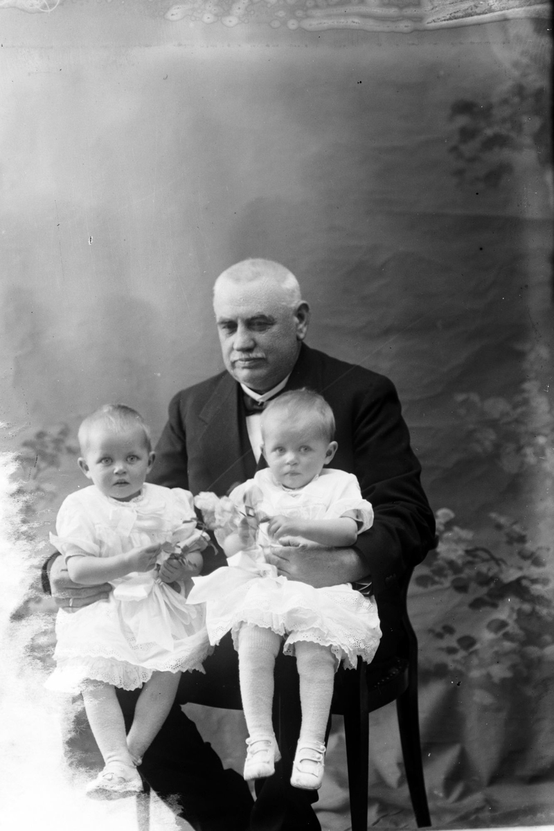 Studioportrett av en mann og to barn.