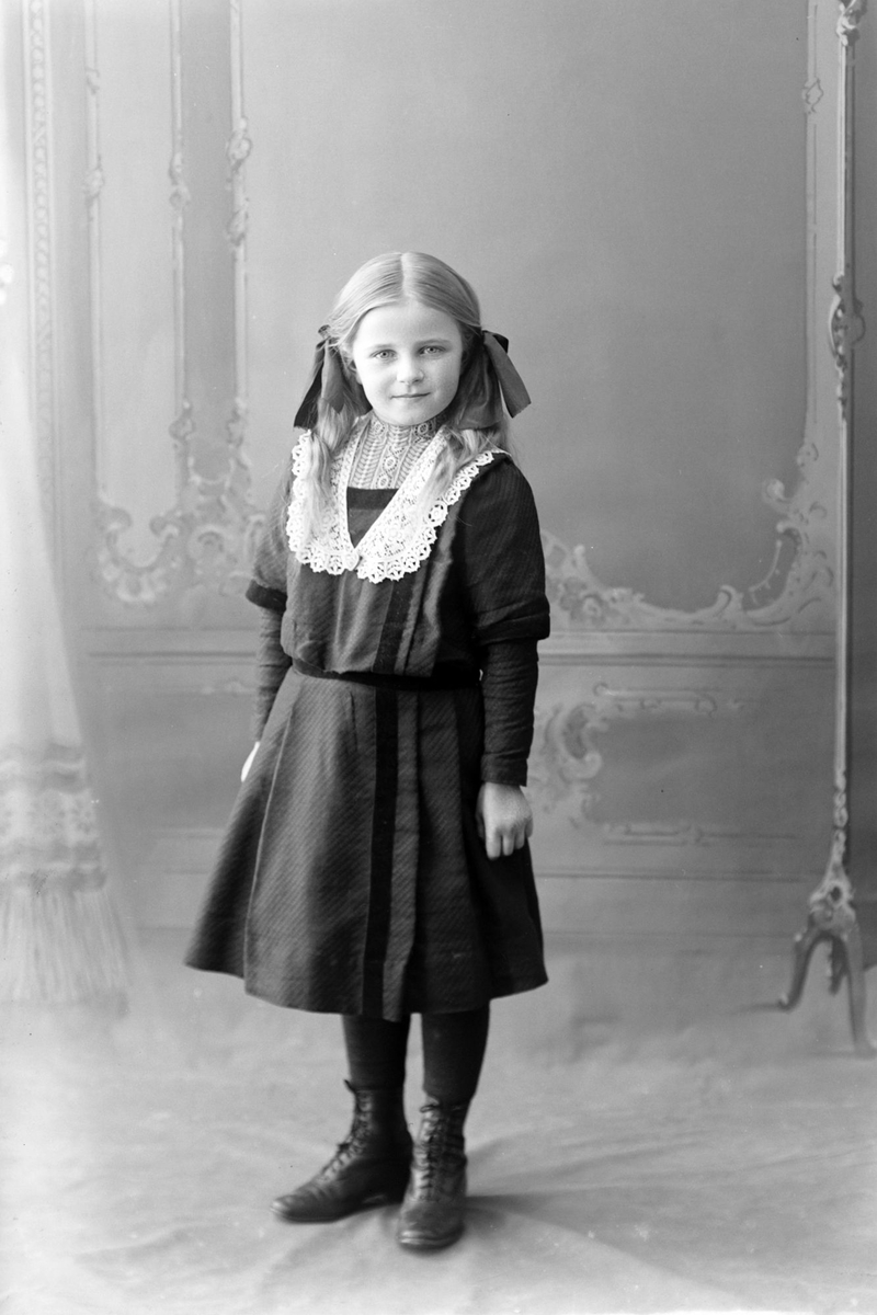 Studioportrett av en ung pike med sløyfer i håret.