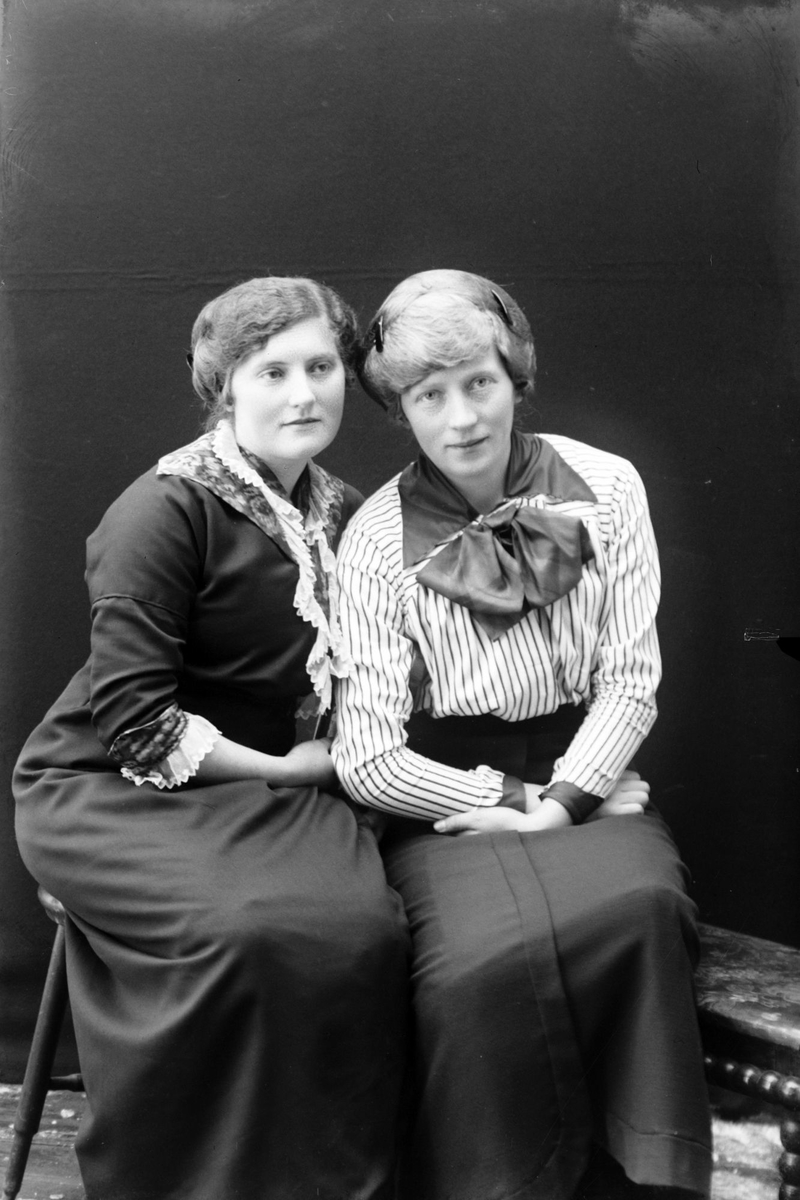 Studioportrett av to kvinner som sitter.