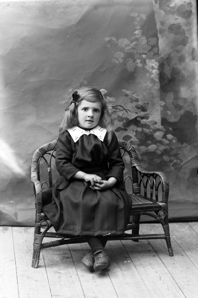 Studioportrett av en ung pike sittende på en benk.
