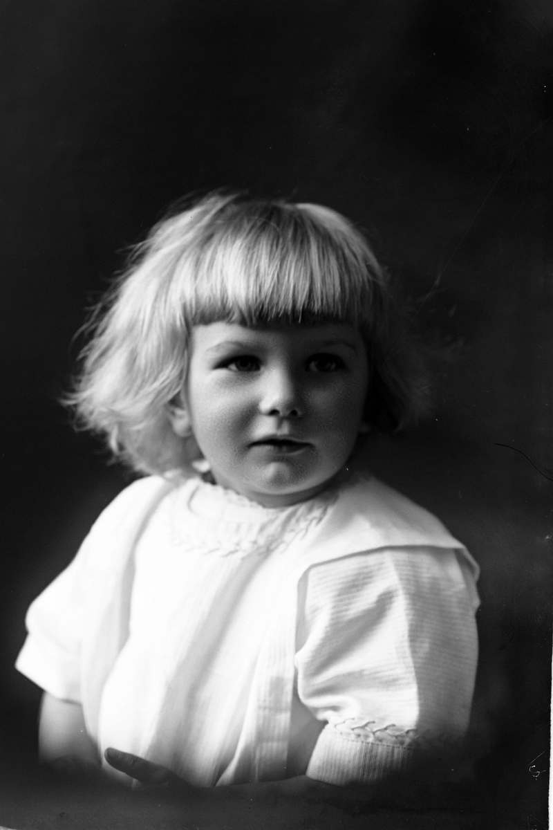 Studioportrett i halvfigur av en liten jente.