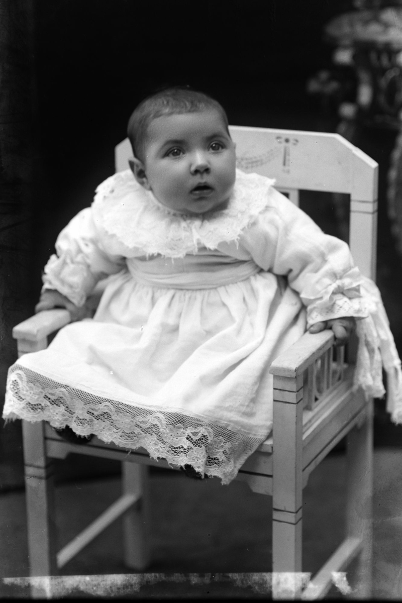 Studioportrett av et lite barn sittende på en stol.