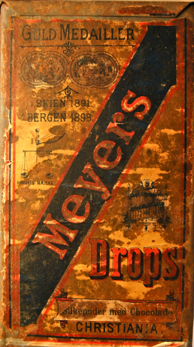Forsiden på dropsboksen merket: Meyers Christiania. Drops, Silkepuder med Chocolade. Guld Medailler Skien 1891, Bergen 1898.